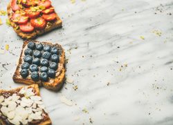 Toast topped with fresh fruit on marble background, horizontal composition with copy space