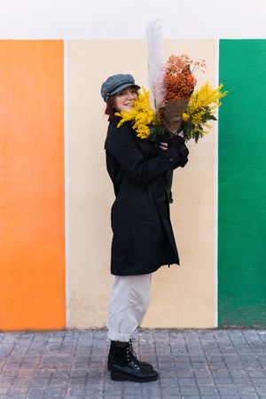 Woman with flowers smiling against colorful wall
