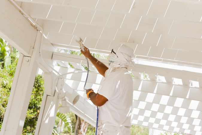 House Painter Spray Painting A Deck of A Home