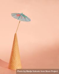 Ice cream cone with cocktail parasol on pink background 5zAko0