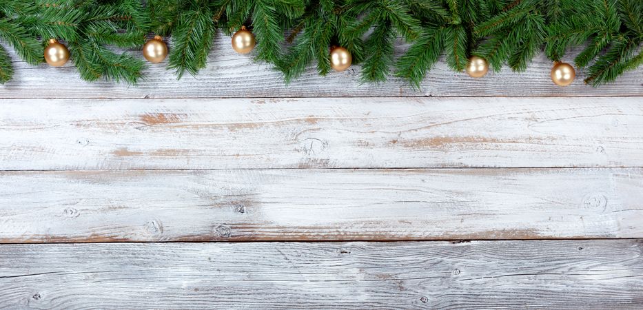 Christmas evergreen branches and golden ornaments on vintage wooden planks