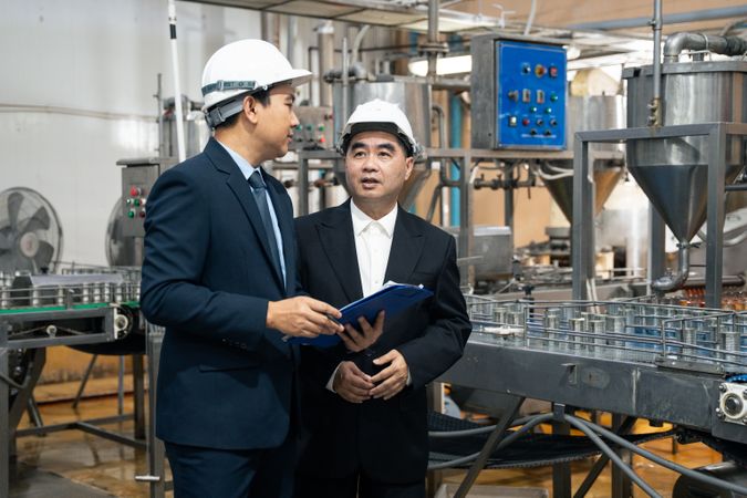 A businessman inspecting canned fish on conveyor belt at the factory
