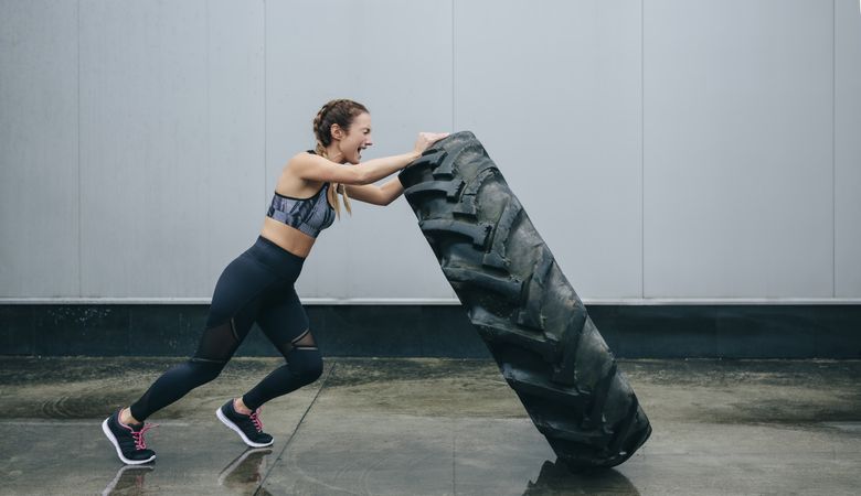 Sportswoman doing cross-training lifting a tire