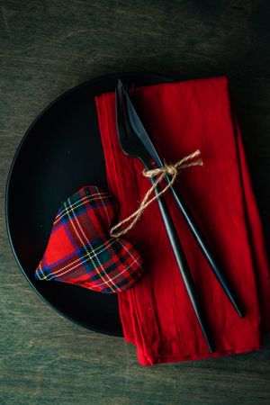 Top view of Valentine's table setting with red napkin and tartan heart