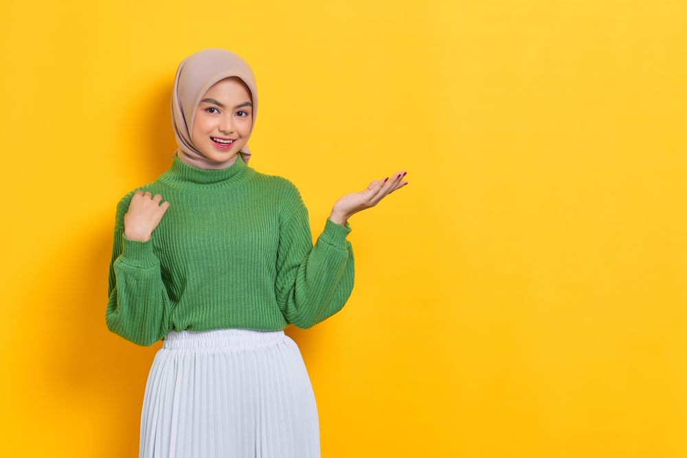 Happy woman in headscarf with her palm up towards copy space