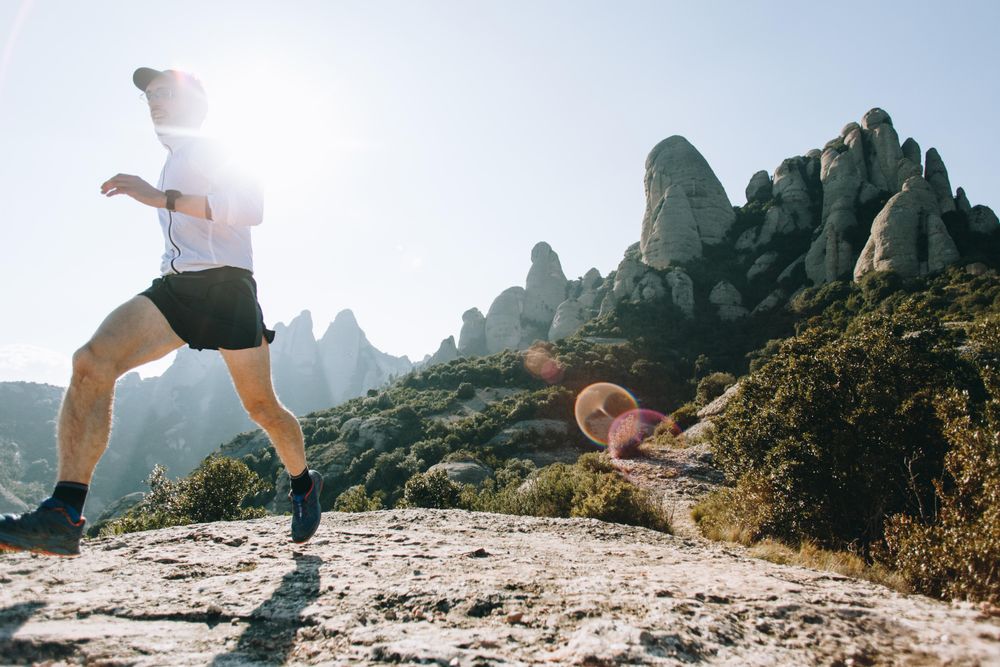 Male running on rugged terrain outside with sun flare