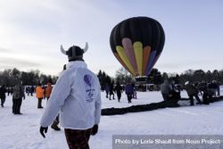 Hudson, WI, USA - February 8th, 2020: Man in Viking hat looking at hot balloon in the winter 4BJkd4