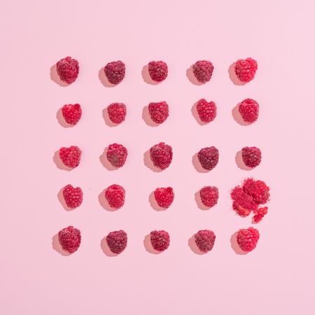 Row of raspberries on pink background