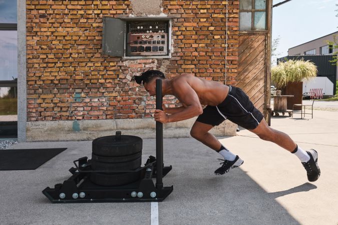 Black guy pulling weights in outdoor gym
