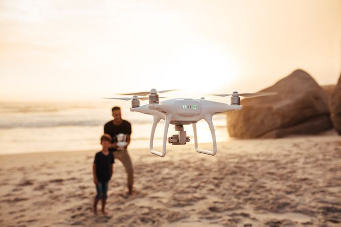 Drone being operated by male with child watching beside him
