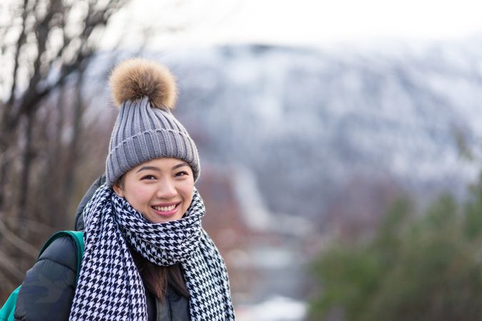 Asian female tourist in warm clothing at snowy nature