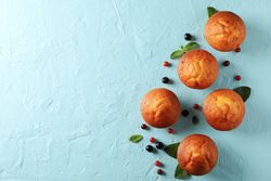 Composition with muffins and berries on blue background, top view