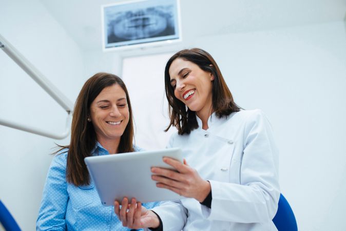 Dentist speaking with client showing document with information