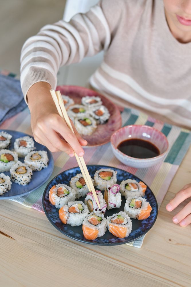 Crop boy enjoying tasty rolls in kitchen at home