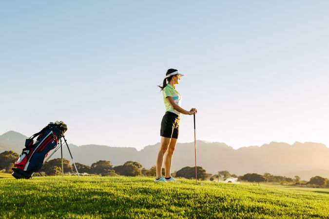 Female golfer holding golf club on field