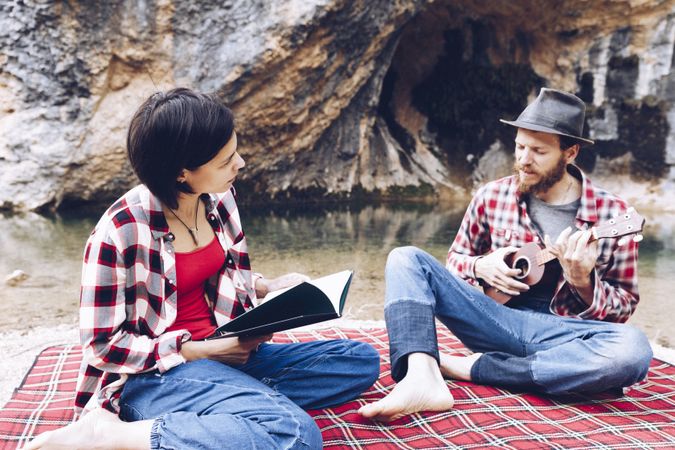 Chilling couple with book and guitar on shore