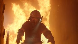 Firefighter running down stairs with fire behind