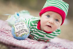 Infant Baby On Blanket With Babys First Christmas Ornament