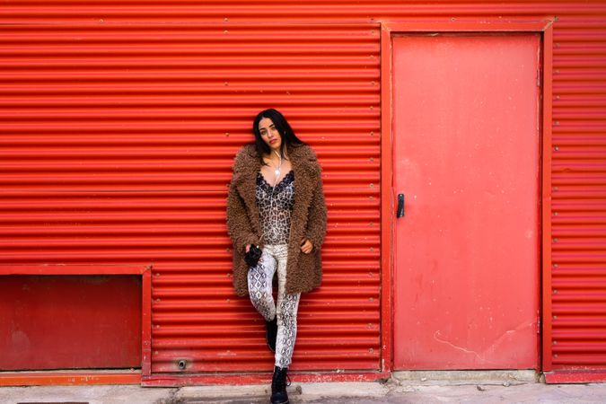 Trendy woman with smartphone near wall