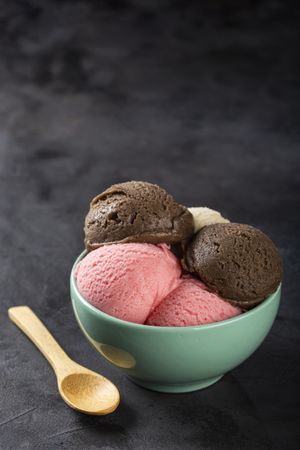 Bowl with Neapolitan ice cream on dark background.