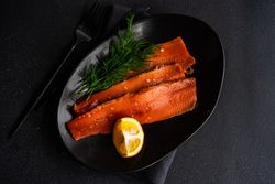 Looking down at raw herring fish with dill and lemon served on plate