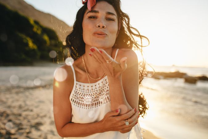 Attractive woman enjoying a summer day on beach blowing kiss at camera