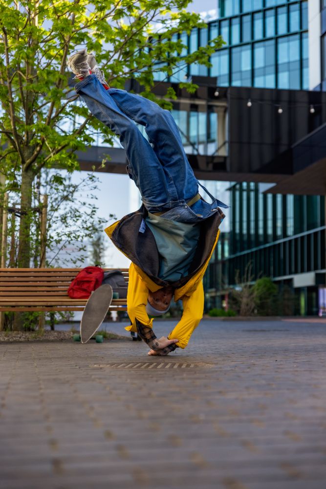 Vertical Screen: Young And Athletic B-Boy Breakdancing To Break Beats On The City Street Among Modern Buildings Alone With A Speaker.