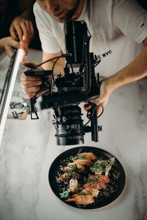 Cropped image of photographer taking photo of sushi plate