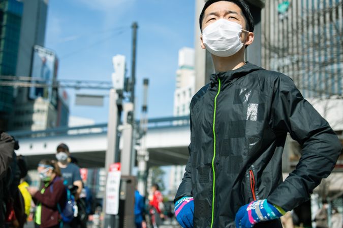 Man in jogging uniform and facemask standing outdoor in city