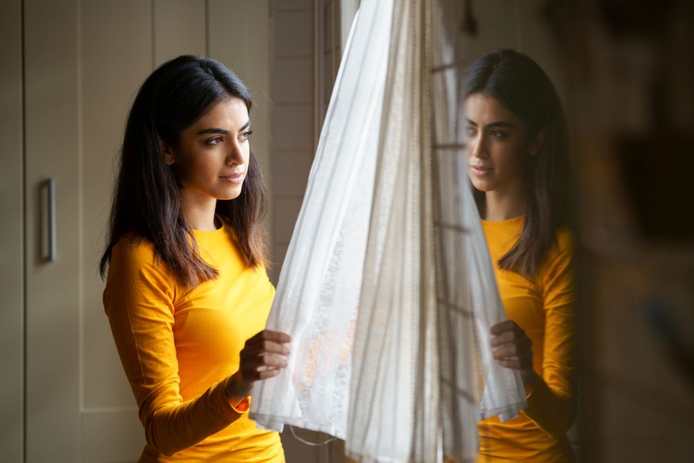 Female opening curtains and gazing out the window