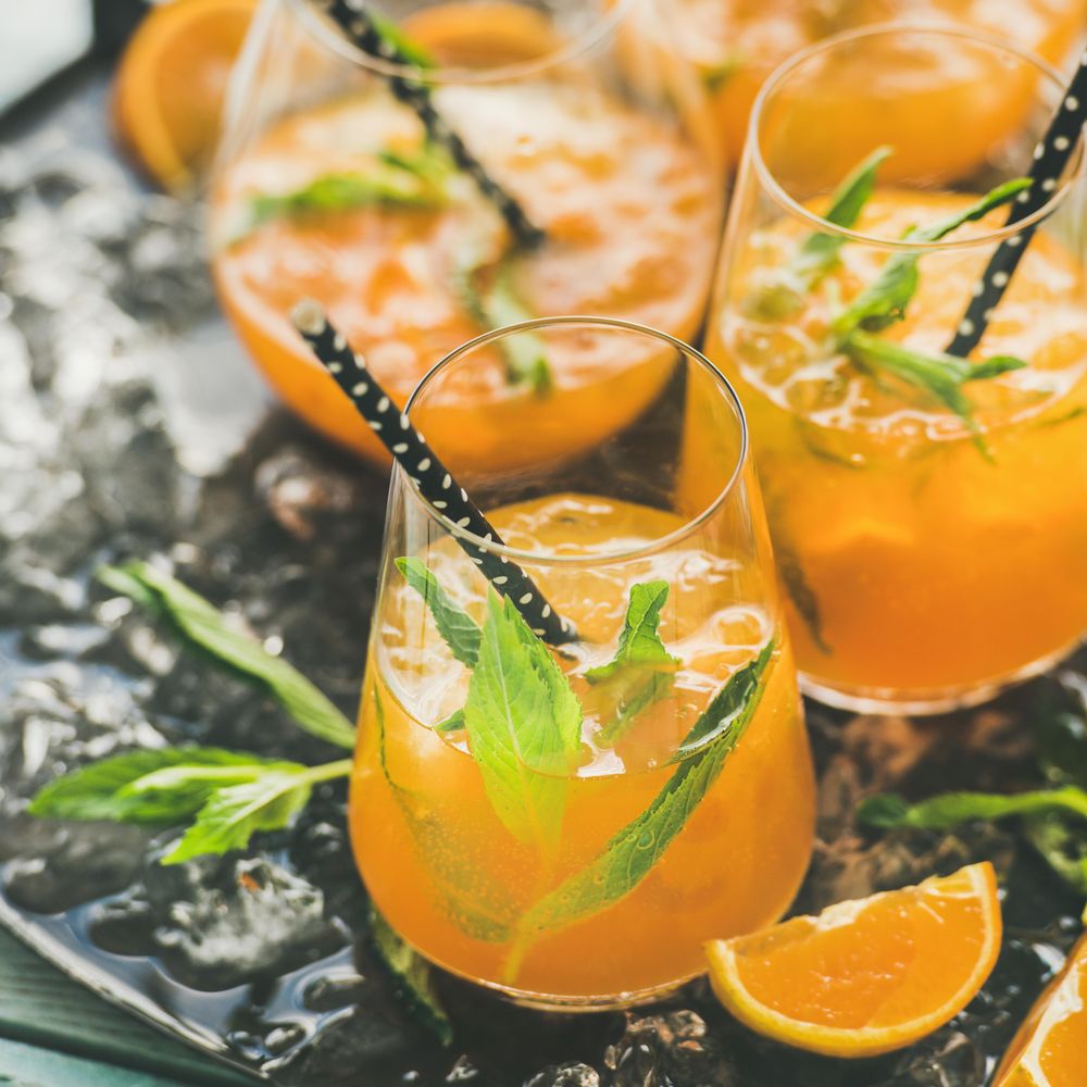 Orange cocktails in glass with garnish, and eco-friendly straws