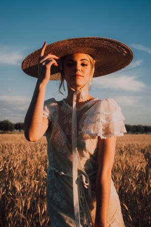 Woman in big round hat in middle of wheat field