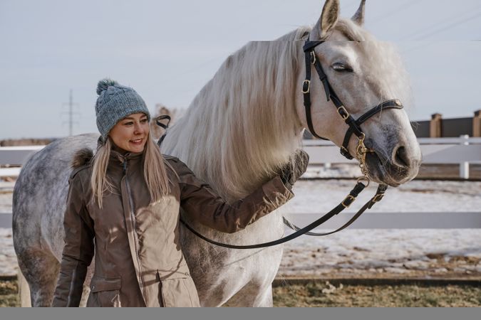 Warm dressed woman with gray horse outside