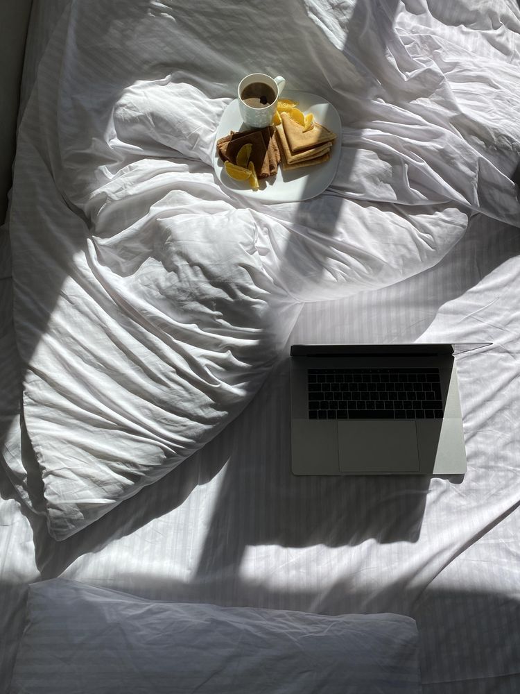 Plate of crepes in bed with coffee and laptop