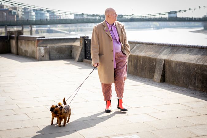 Man walking by river with two dogs