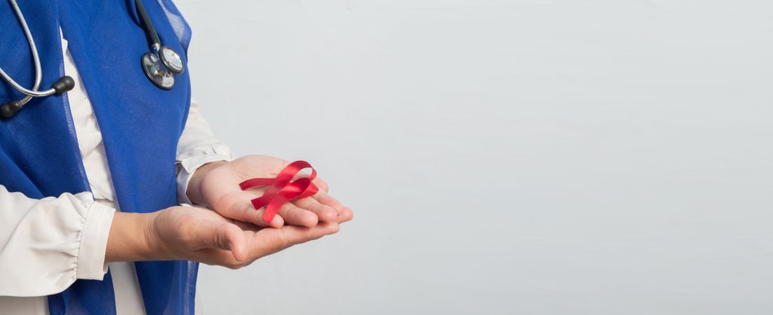 Happy Muslim Female Asian doctor or nurse holding Red ribbons, HIV awareness concept, world AIDS day, world cancer day with copy space