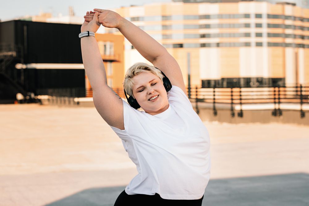 Athletic woman stretching her arms ahead of her workout on a rooftop