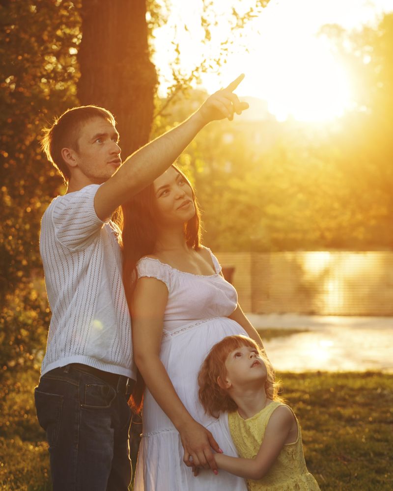 Side view of young family in park at magic hour with father pointing