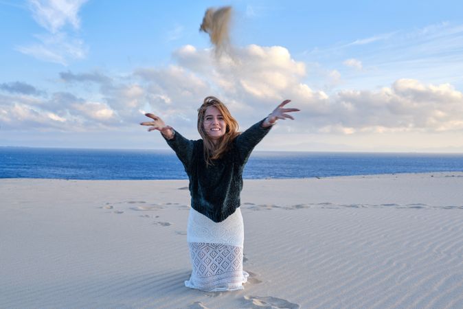 Woman throwing sand on beach