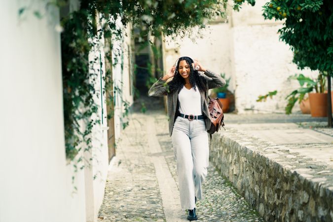 A Stylish Young Woman is Enjoying a Leisurely Stroll Through a Quaint Cobblestone Street