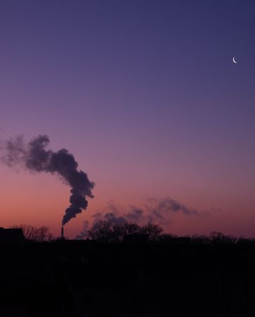 Smoke being discharged into pink purple morning sky, vertical