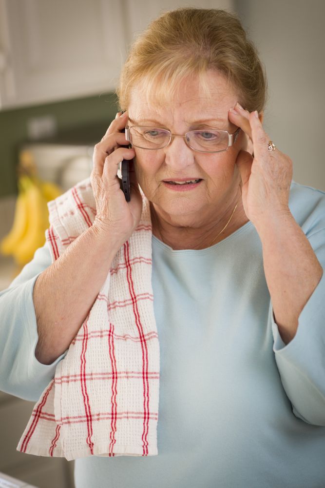 Shocked Older Adult Woman on Cell Phone in Kitchen