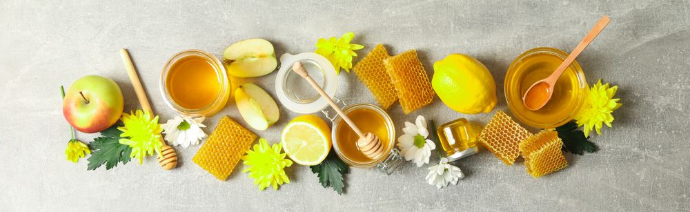 Flat lay with honey, flowers and fruits on grey background, copy space