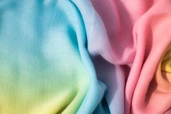 Gradient yellow blue pink and green fabric wavy spiral crumpled background texture with copy space.