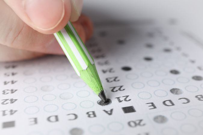 Person with green pencils taking multiple-choice exam
