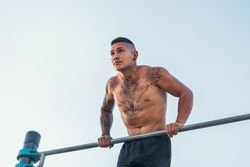 male athlete doing dips on a bar outdoors