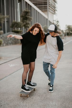 Man helping girlfriend to skate on road