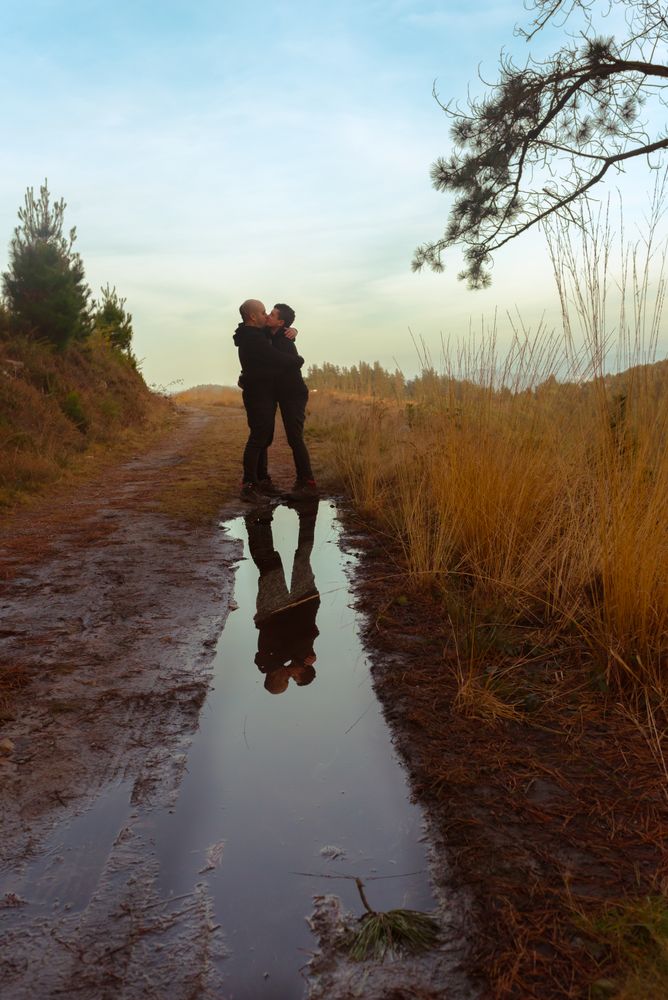 Men hugging and kissing near water puddle
