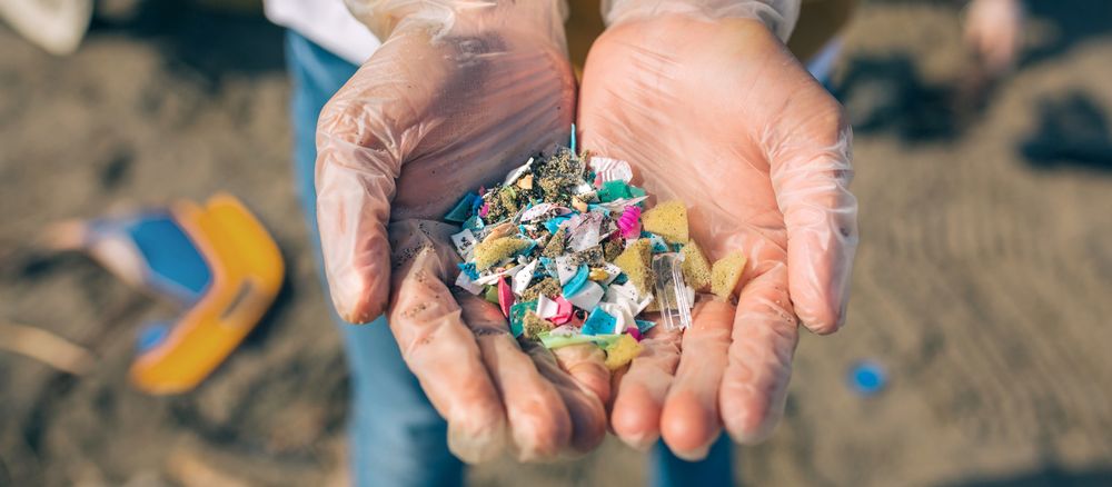 Hands with microplastics on the beach