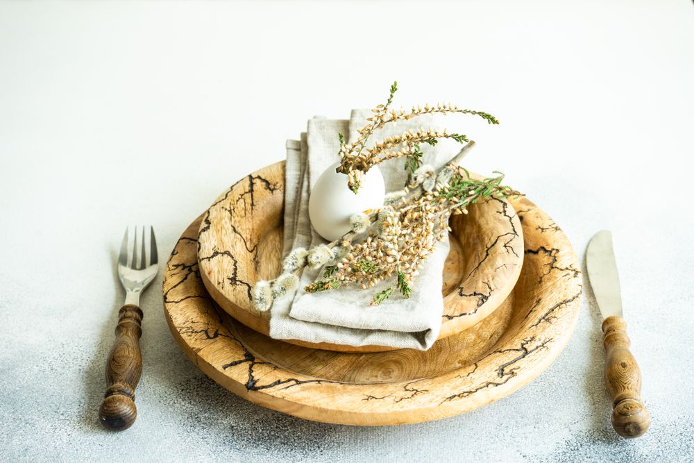 Decorative egg with plant on Easter table setting on rustic plates